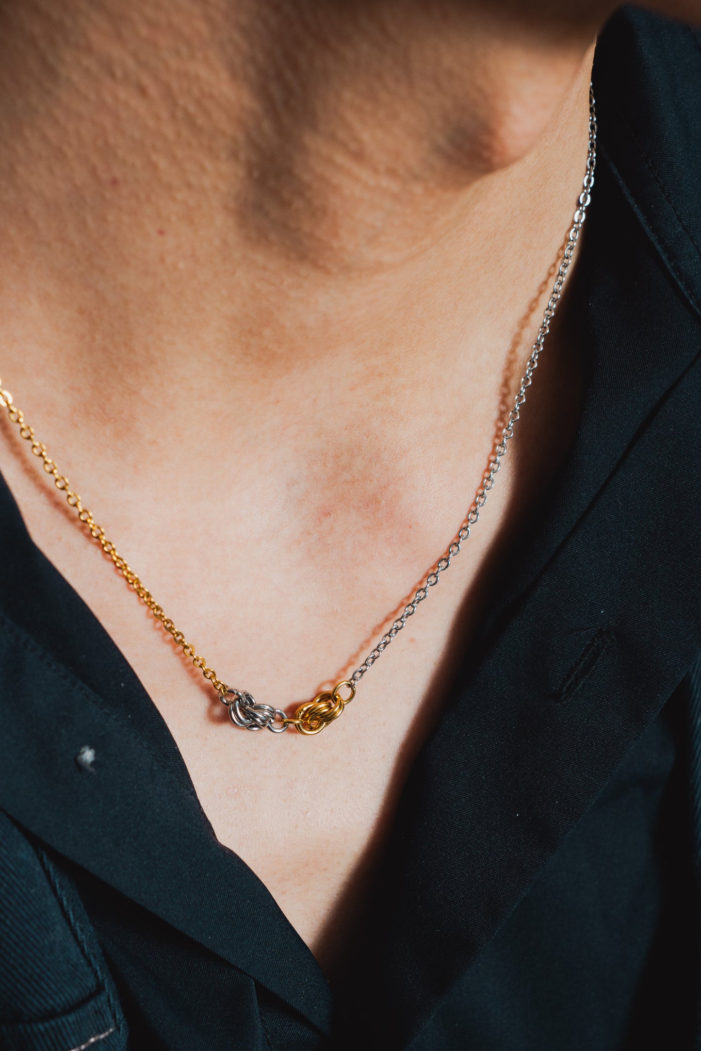 slightly angled view of gold and silver toned knot necklace on neck