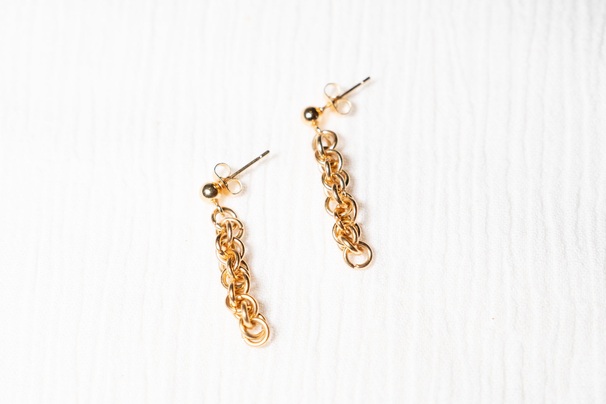 Gold tone chainlink earrings on a white background