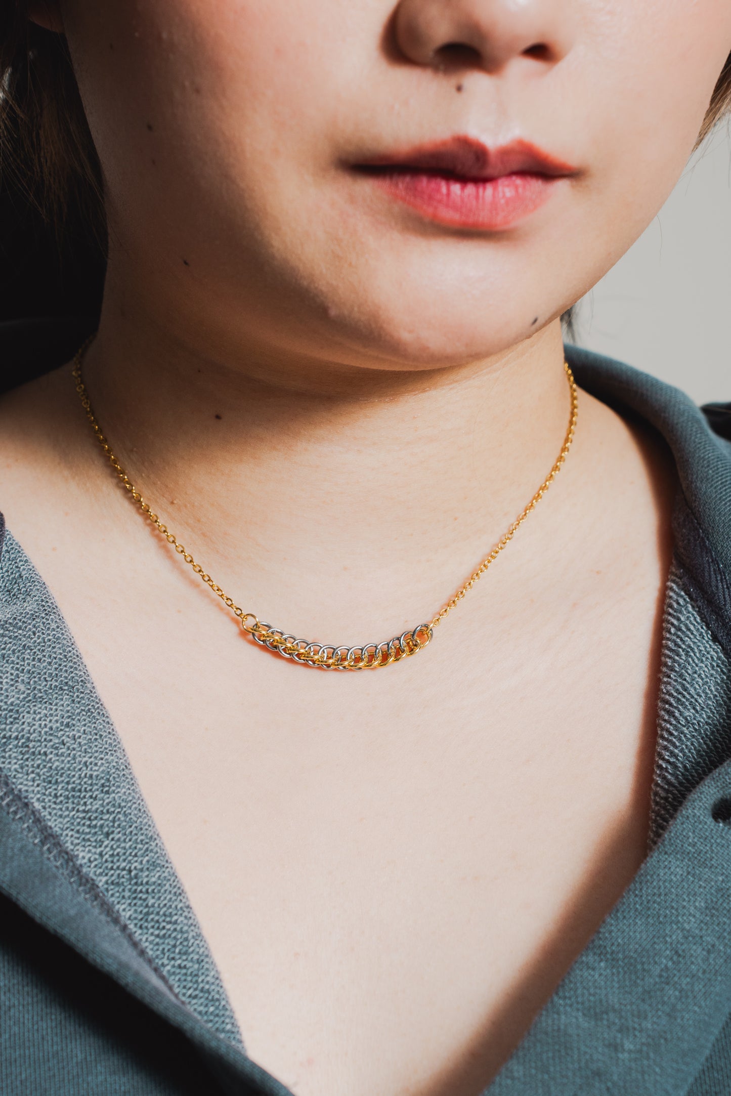 gold and silver tone weave design on gold chain around female model's neck