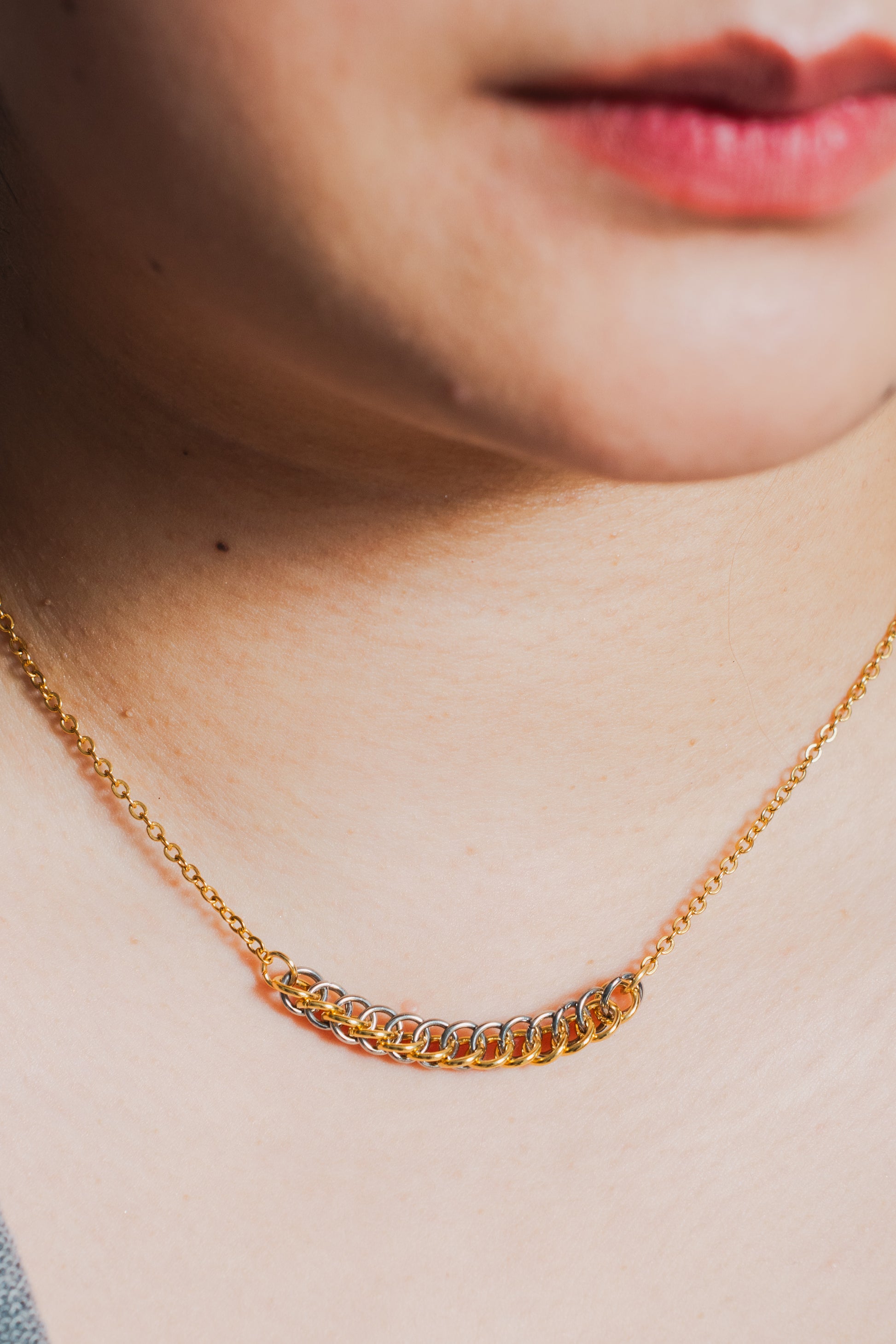 Mixed metal gold and silver tone weave design on gold chain around model's neck