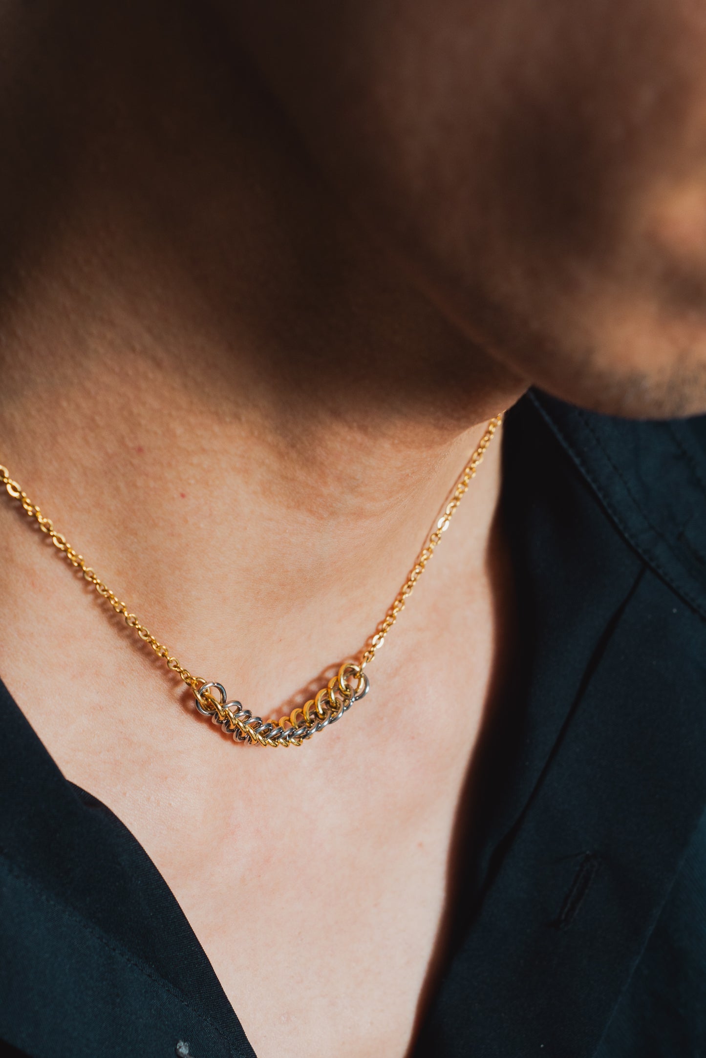 gold and silver tone weave design on gold chain around model's neck