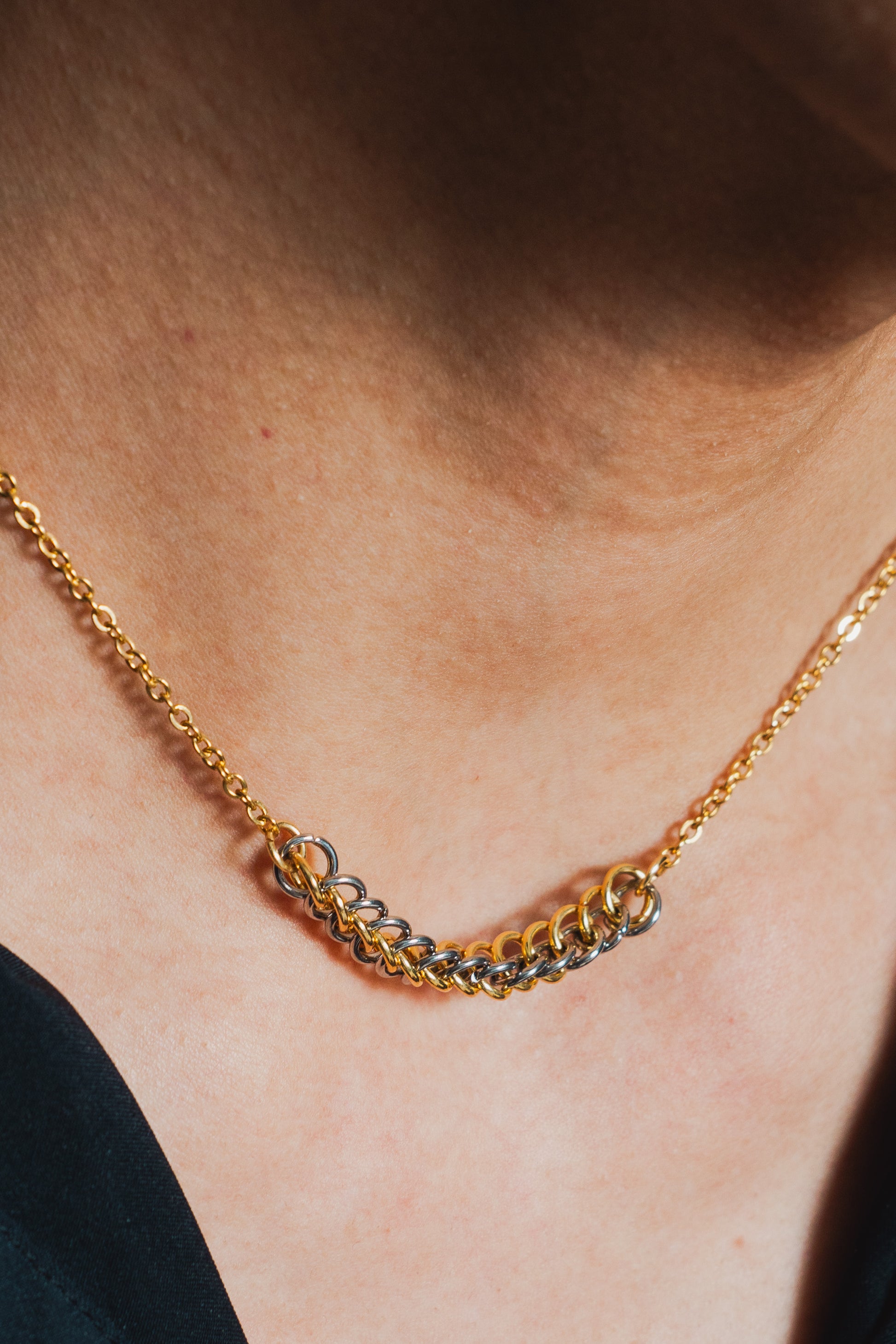 gold and silver tone weave design on gold chain around model's neck