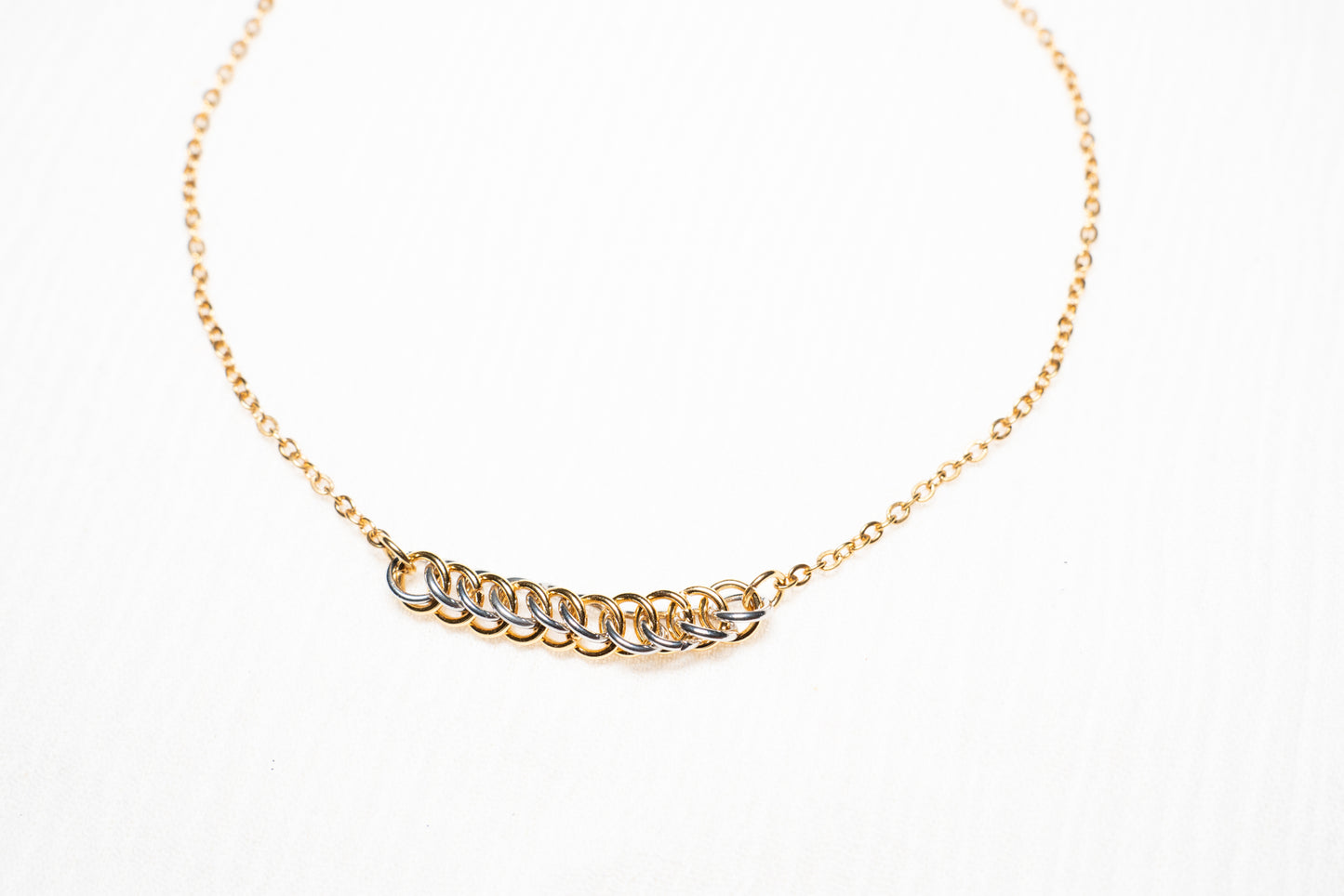 mixed metal gold and silver tone weave design on gold chain with white background