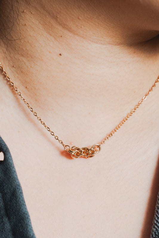Rose gold tone metal weave necklace on model's neck
