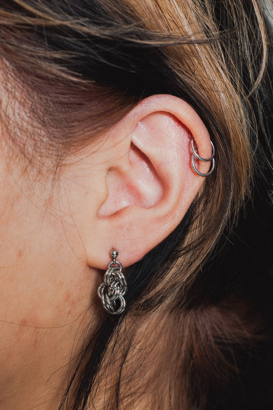 Close picture of a silver tone earring on model's ear