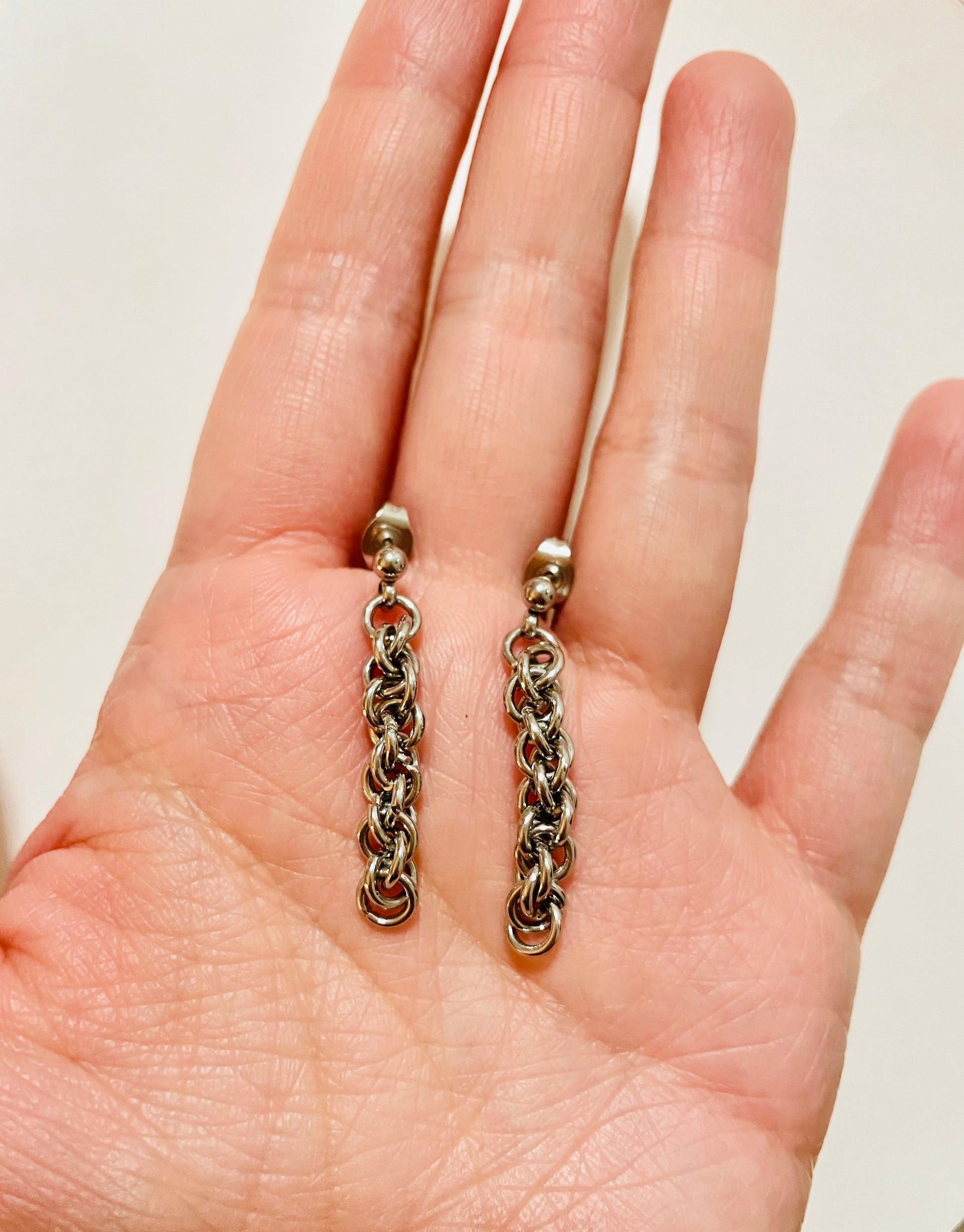 Silver tone chainlink earrings in the palm of a hand