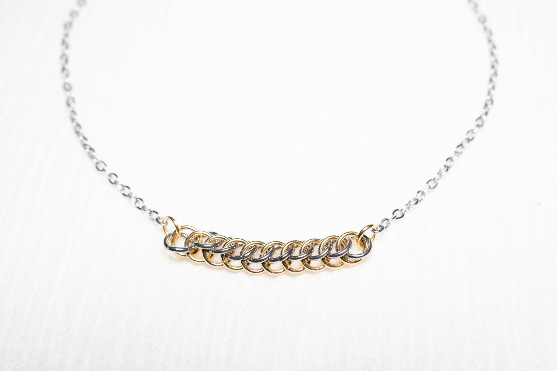 mixed metal gold and silver tone weave design on silver chain with white background